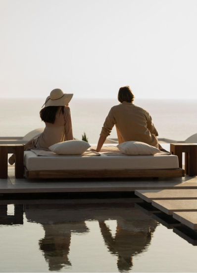 A couple resting on a daybed overlooking the sea
