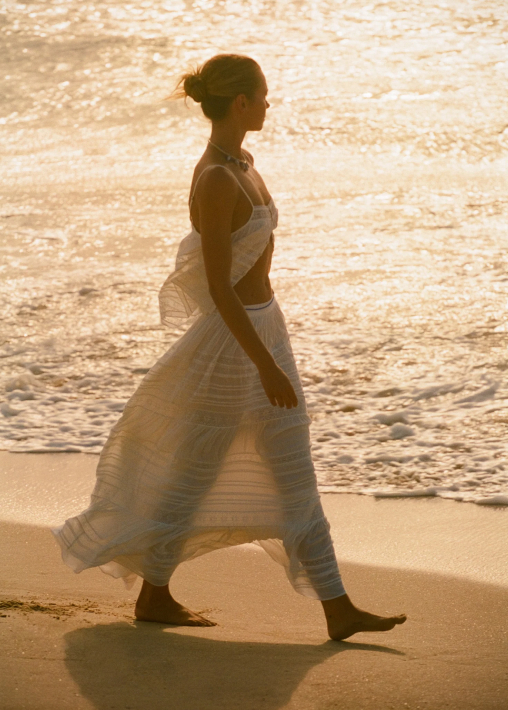 A woman walking along the shoreline at golden hour